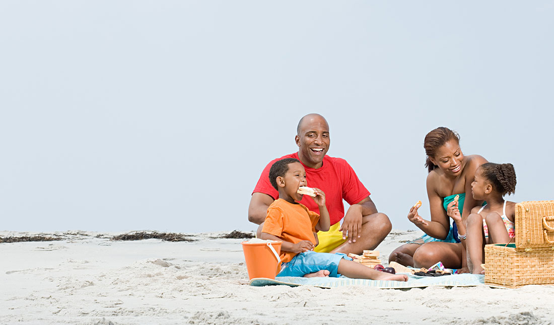 Smiling African American family eating lunch on a beach